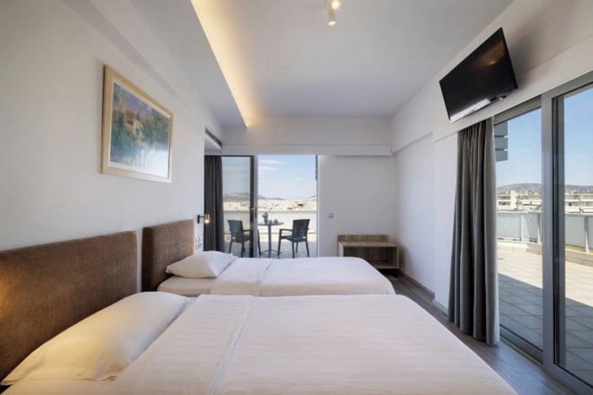 A hotel room with two beds, a television, and a balcony with a view.