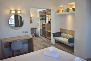 A hotel room with a bed, a desk, a chair, a sofa, a mirror, and a wardrobe. - Xenophon Hotel (Athens)