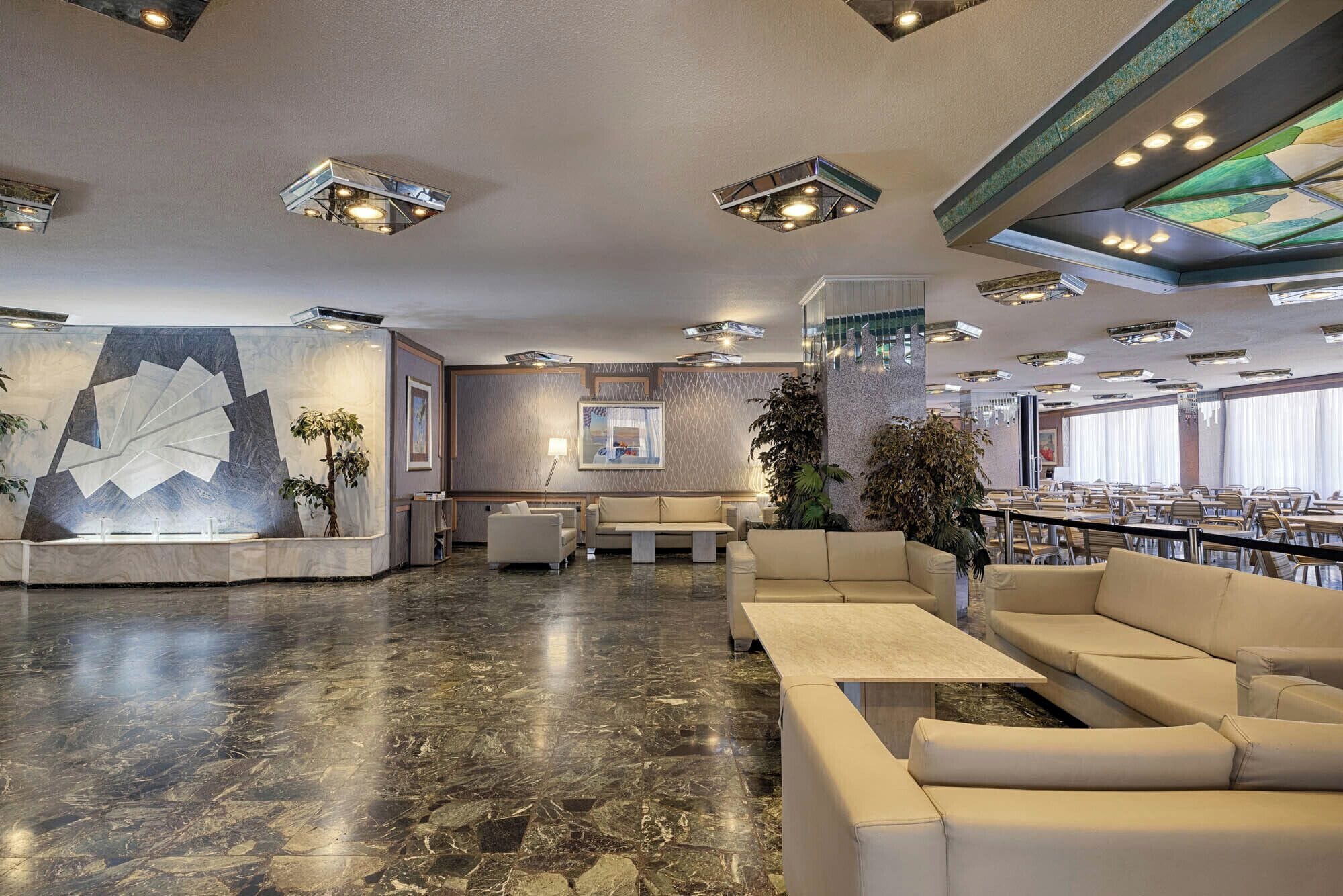 A spacious lobby with a marble floor, seating areas, and a bar.