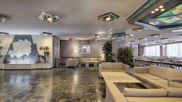 A spacious lobby with a marble floor, seating areas, and a bar.