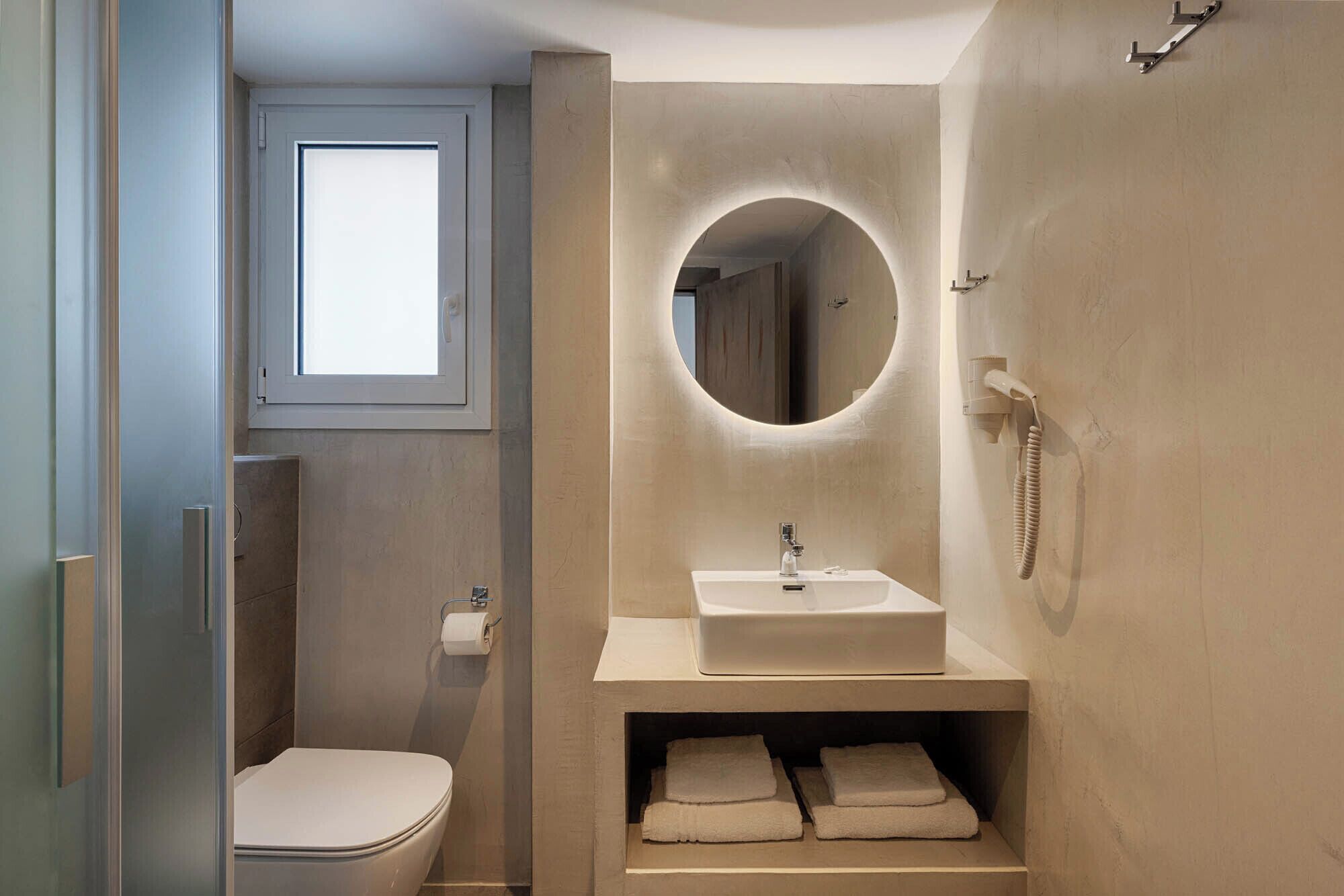 A compact bathroom with a toilet, a sink, and a mirror.