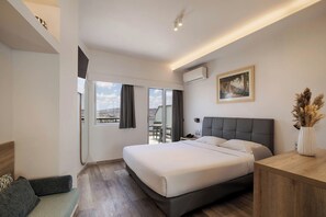 Quarto de hotel com cama, escrivaninha, cadeira e vista para o exterior.
