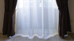 A window with sheer white curtains and dark brown drapes. - Principe di Belmonte (Palermo)