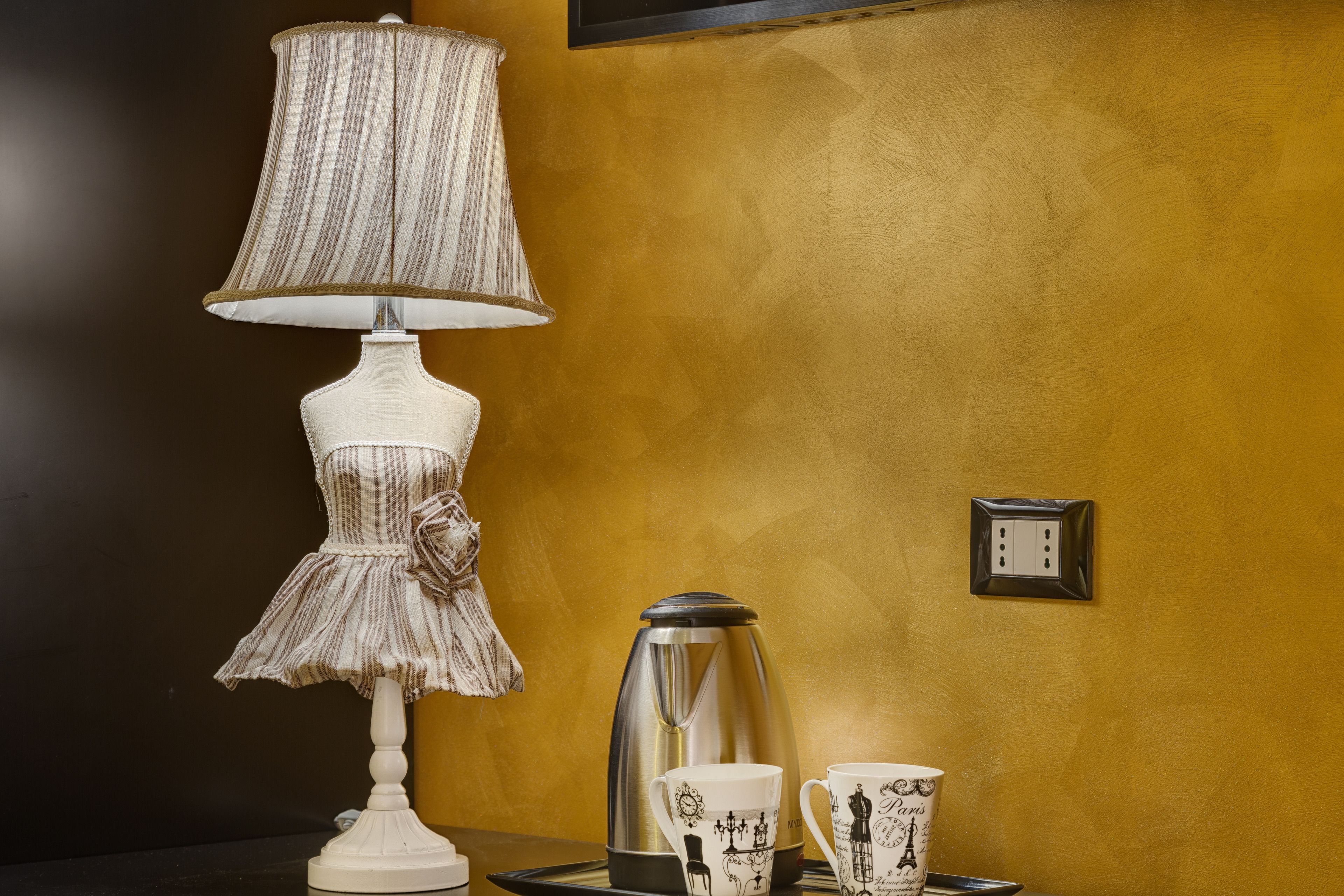 A room with a lamp, a coffee pot, and two cups on a tray.
