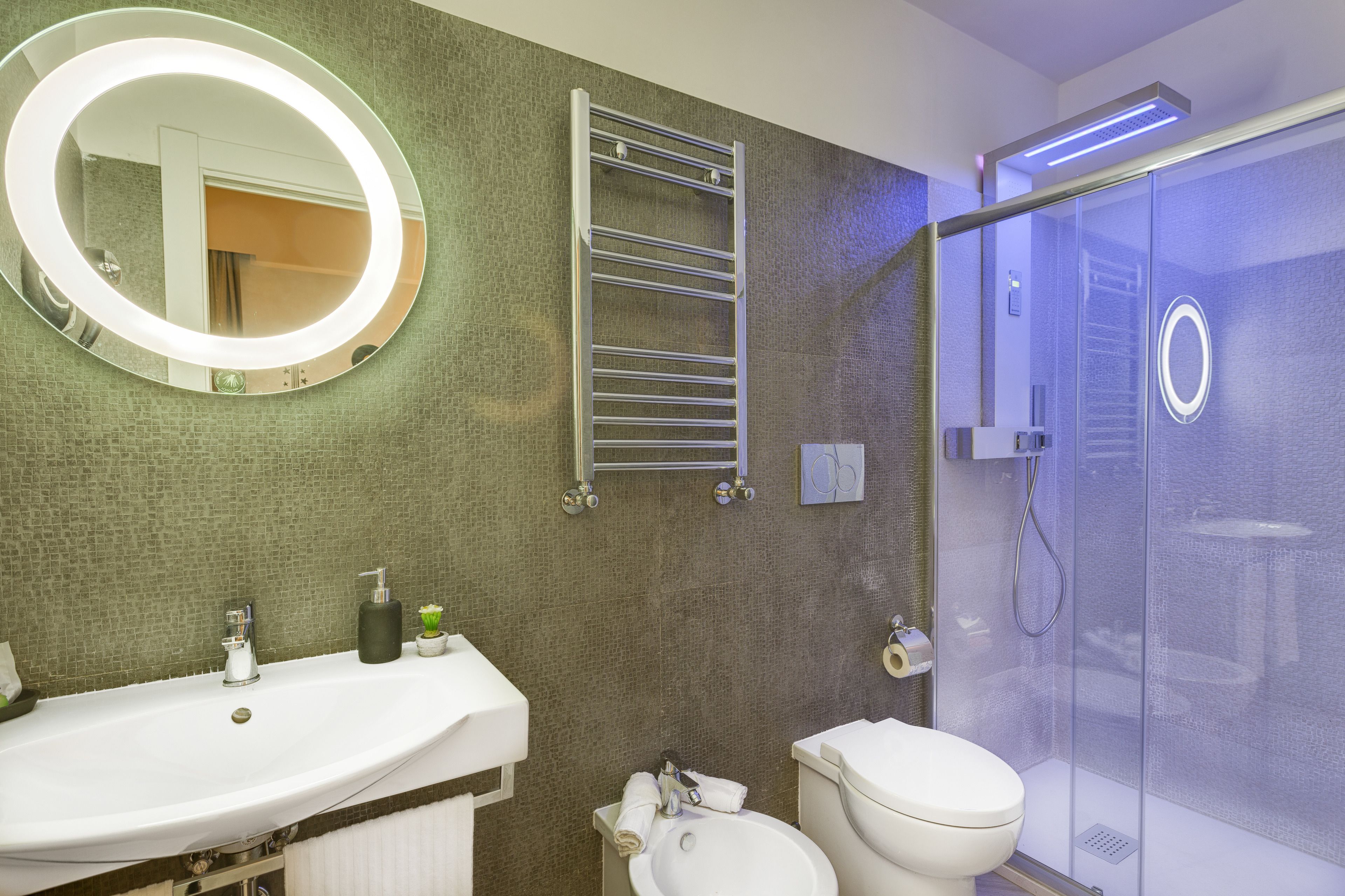 Ein modernes Badezimmer mit großem Spiegel, Handtuchhalter, Toilette und einer Duschkabine.