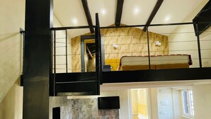 A modern loft-style room with a wooden herringbone floor, a large white bowl on a textured backsplash, and a bunk bed with a wooden headboard. - Excellence Suite (Rome)
