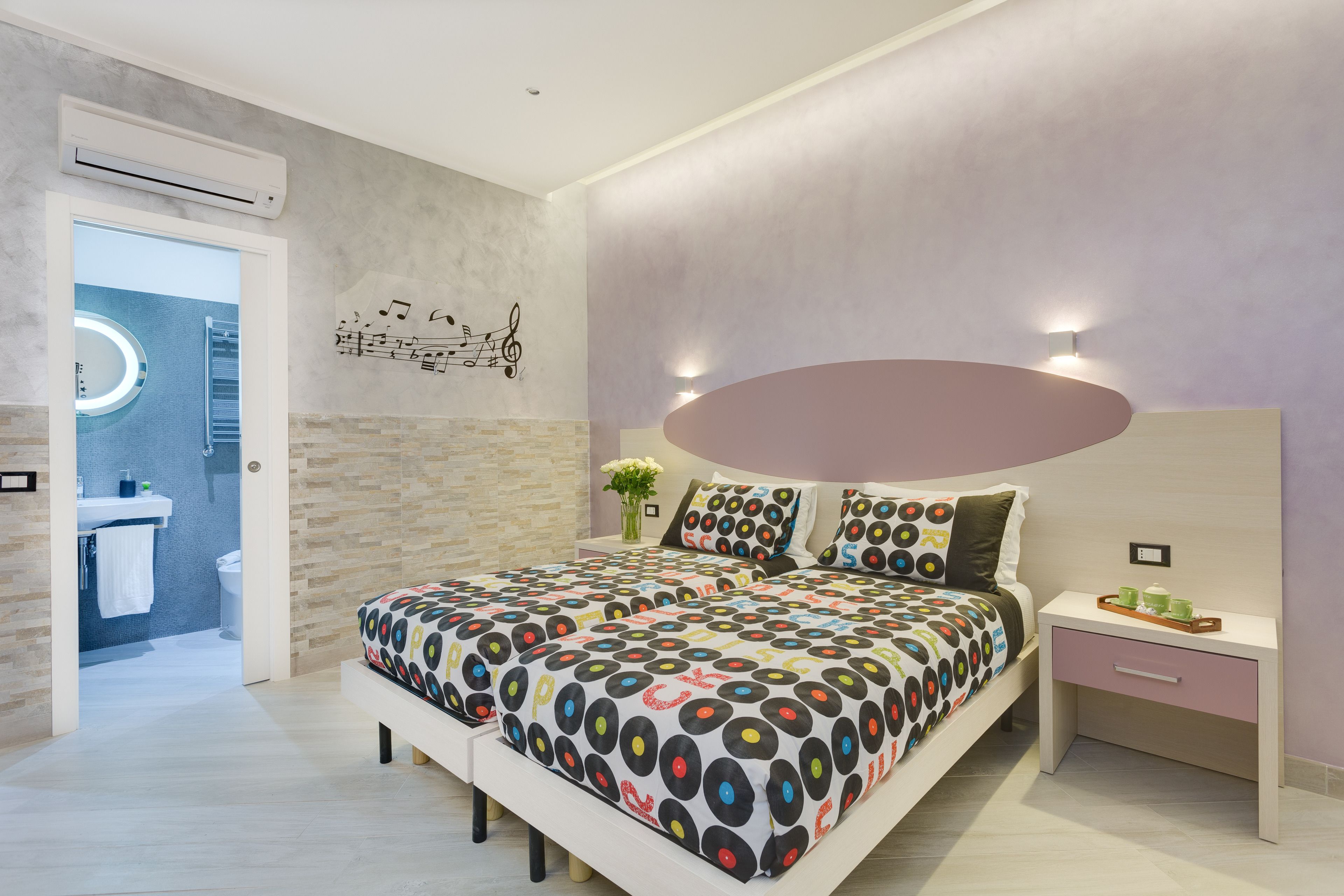 A modern bedroom with a bed, bedside table, and a wall-mounted light fixture.