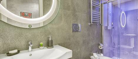 Un baño moderno con un lavamanos grande, inodoro y cabina de ducha de vidrio.
