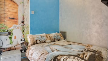 Ein Schlafzimmer mit blauer Wand, einem Bett im Vintage-Autodesign, einem weißen Roller und einer Holztür.