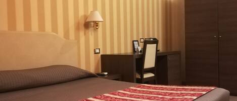 Quarto de hotel com uma cama grande, uma escrivaninha e um guarda-roupa.