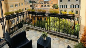 A balcony with outdoor furniture, a view of surrounding buildings, and a clear sky. - Excellence Suite (Rome)