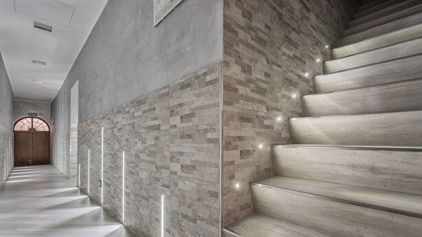 A modern hallway with a wooden staircase and a textured wall. - Excellence Suite (Rome)