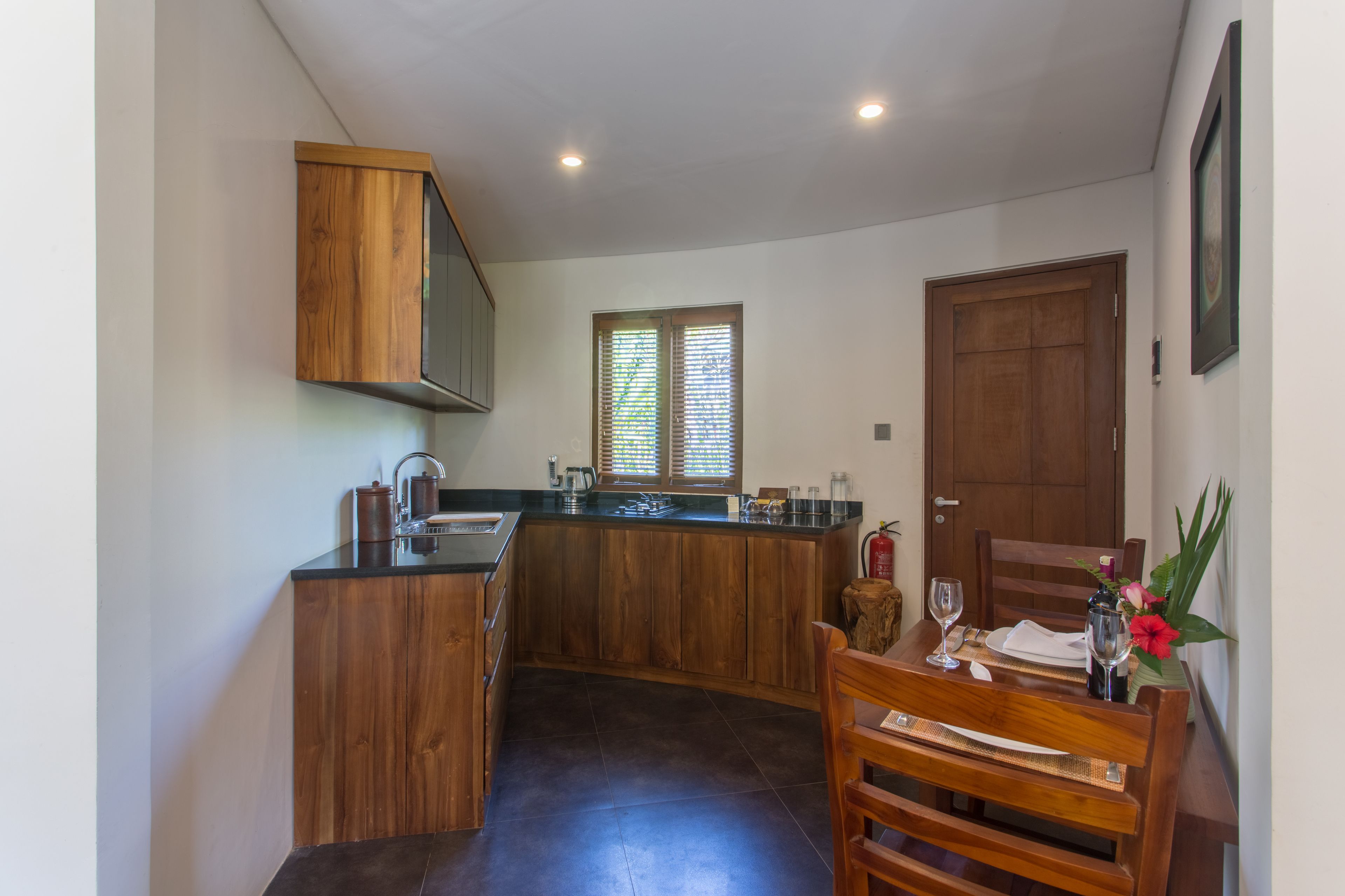 A kitchen with wooden cabinets, a sink, and a dining area with a table set for two.