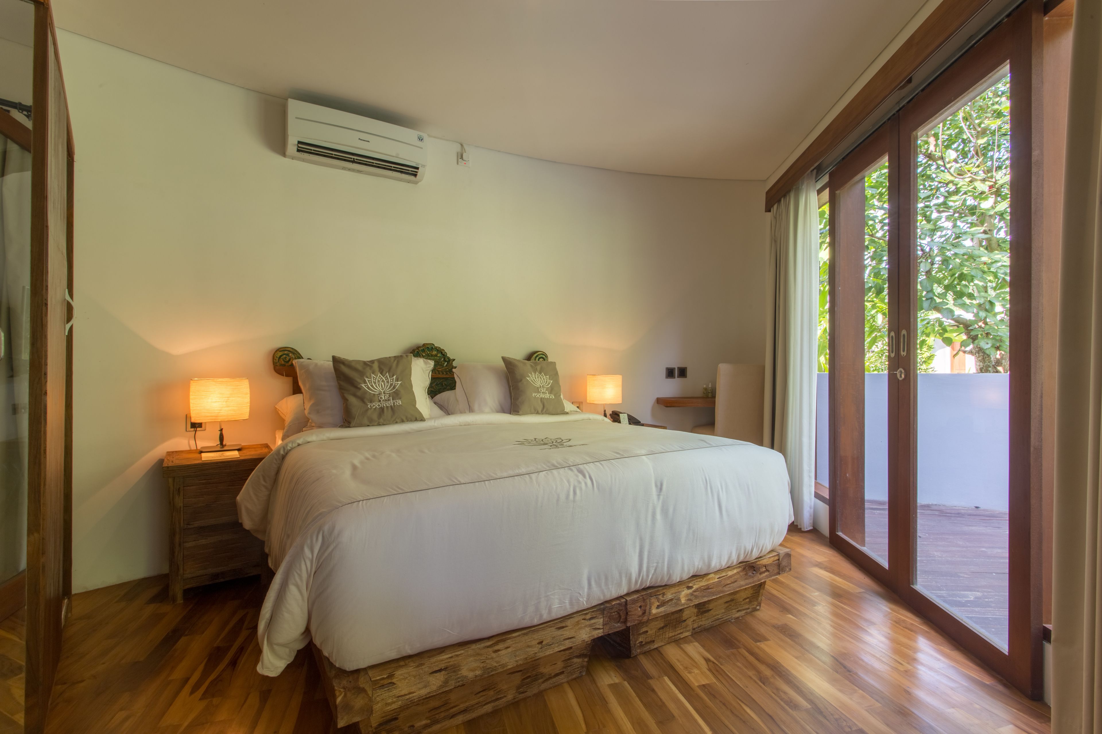 Un dormitorio con estructura de cama de madera, ropa de cama blanca y dos lámparas de noche.