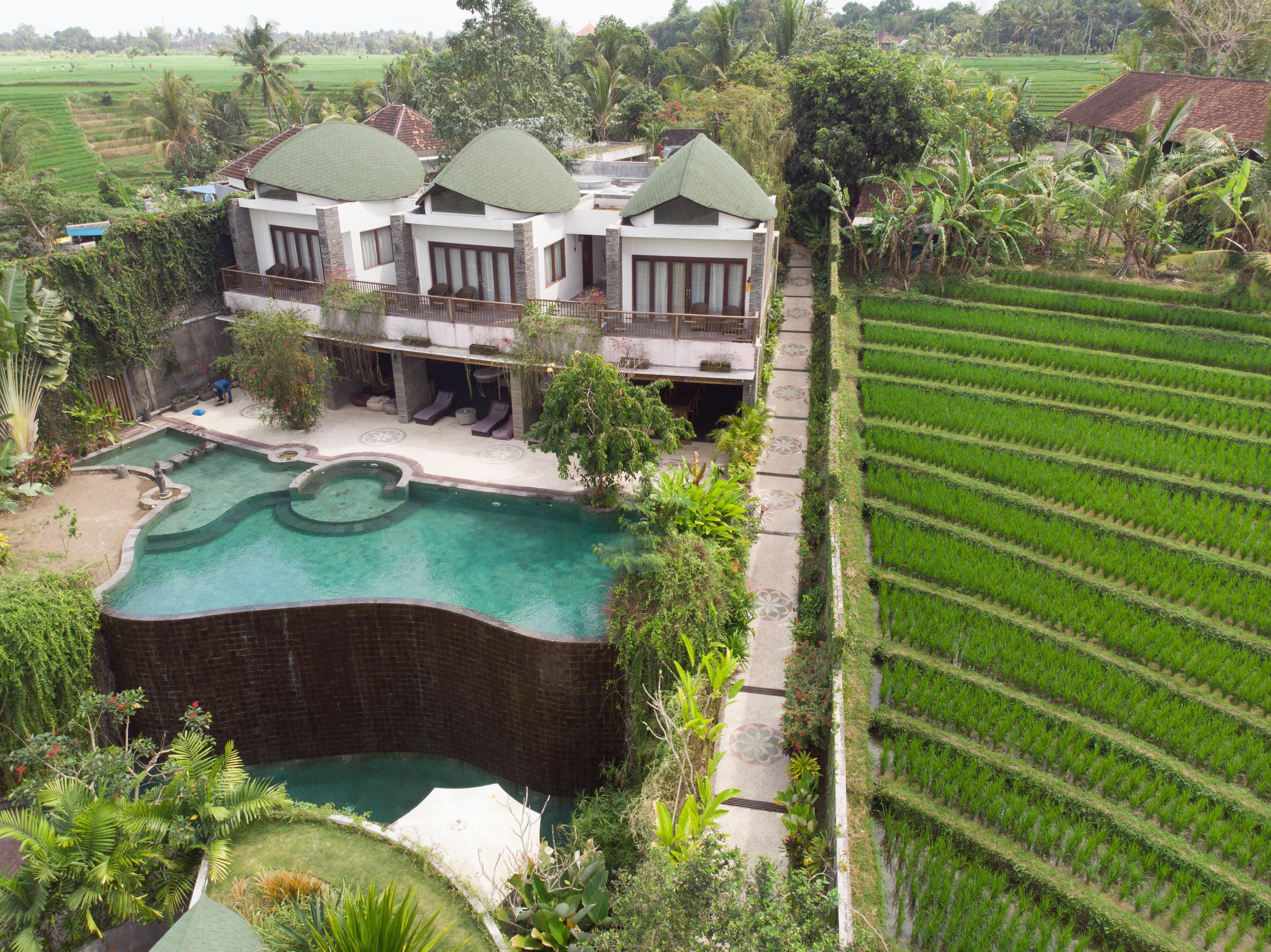 Uma casa grande com piscina e jardins exuberantes ao redor.