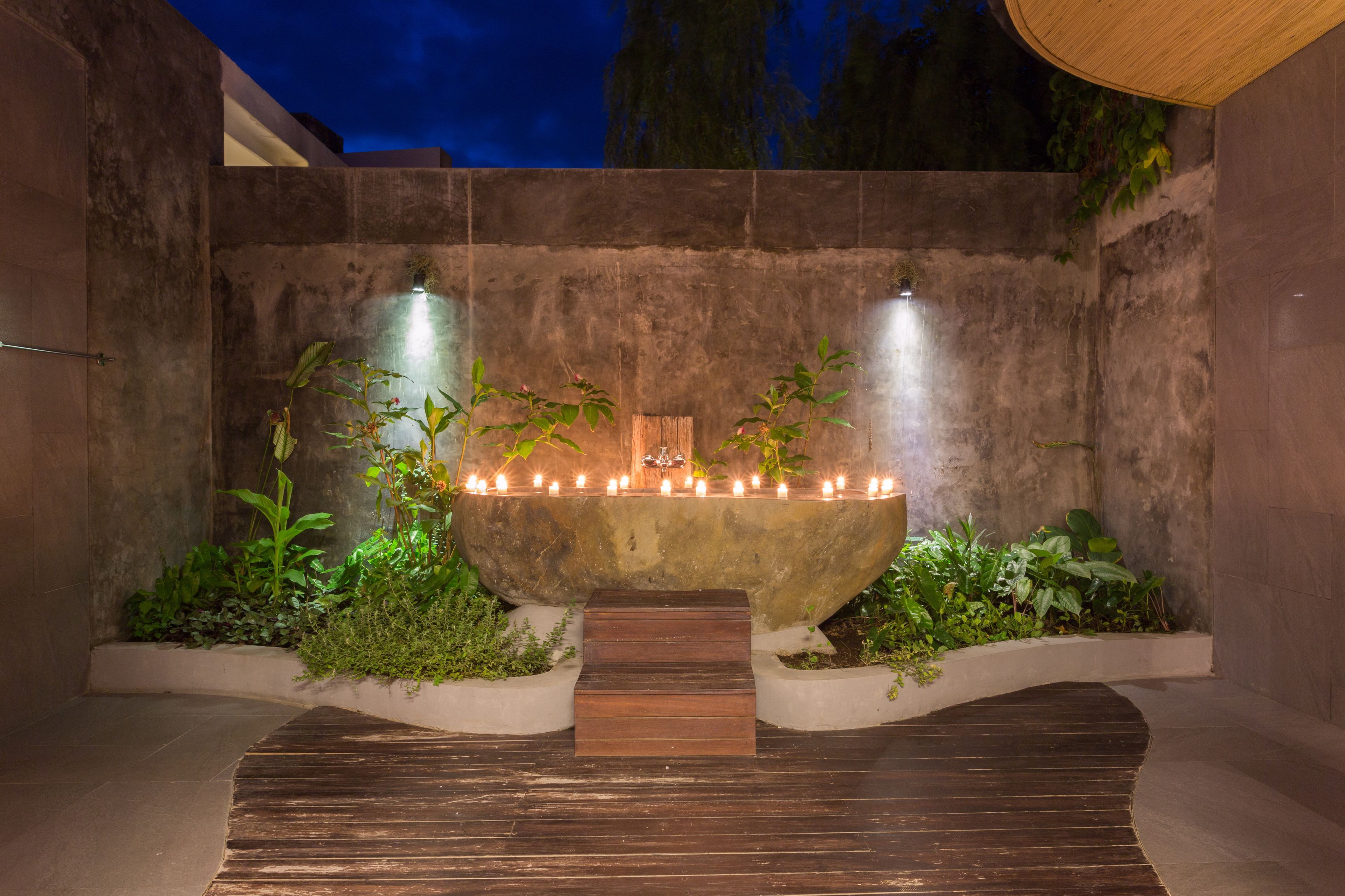 A stone-tiled courtyard with a central water feature, surrounded by plants and a wooden deck.