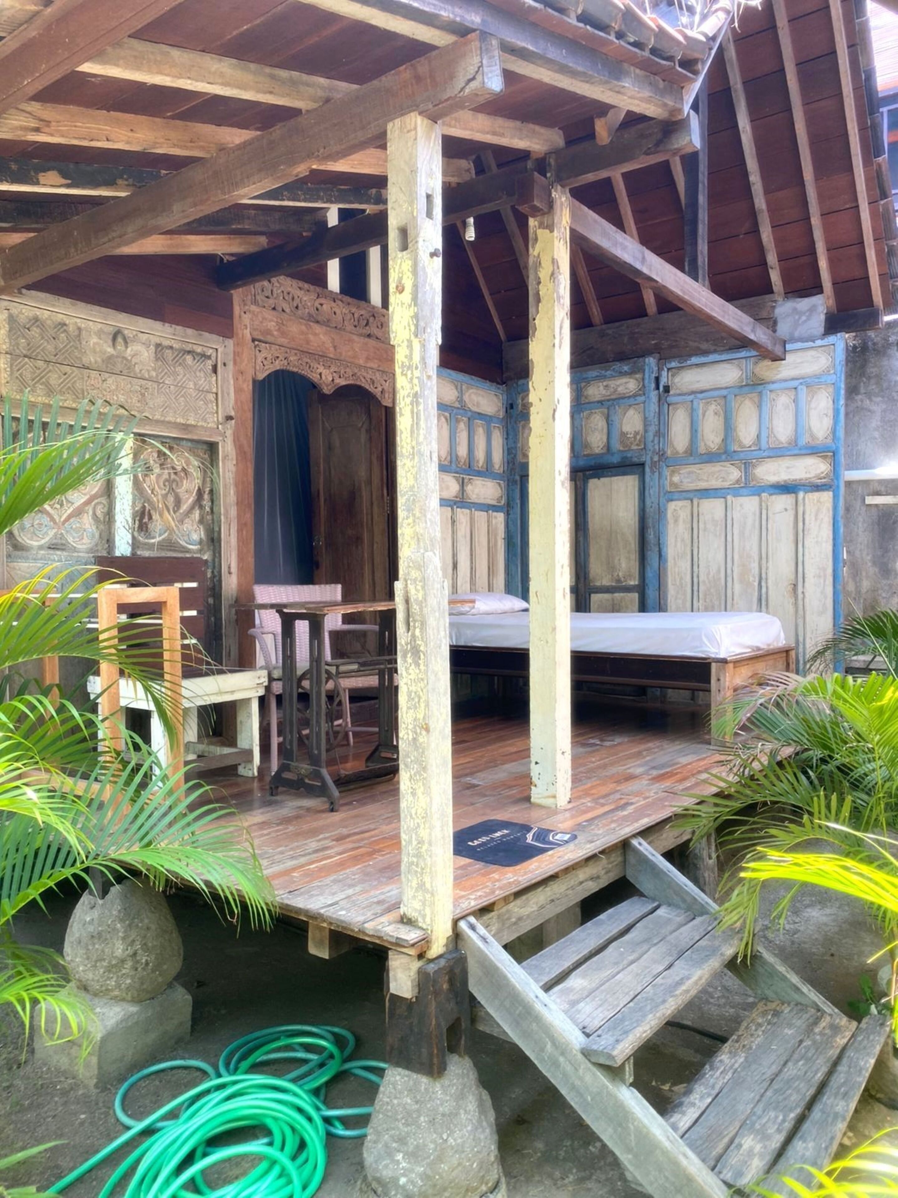 A rustic wooden structure with a bed, a table, and chairs.