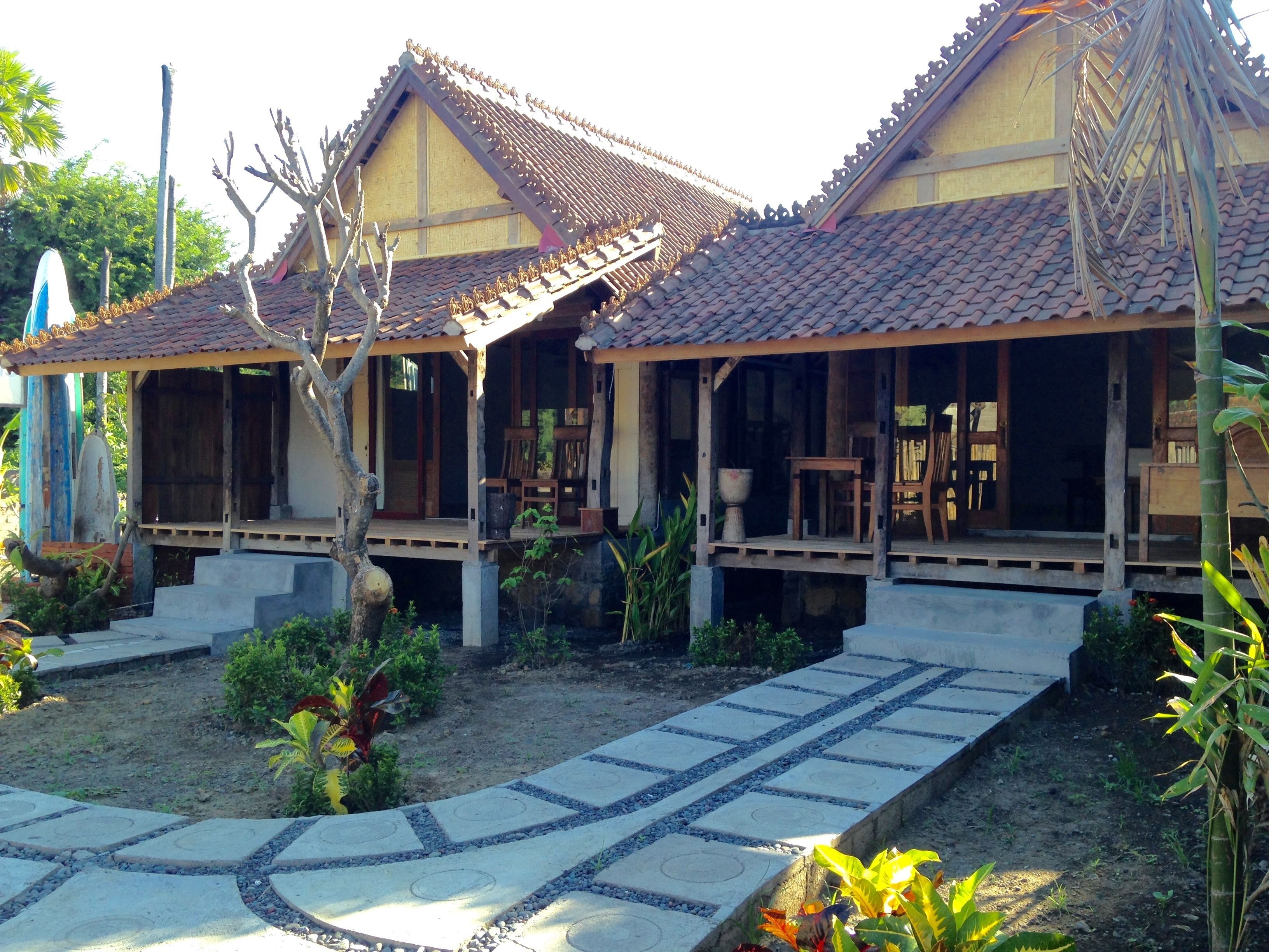 Una casa de madera tradicional con tejado de baldosas, un porche con asientos y un jardín con un sendero de piedra.