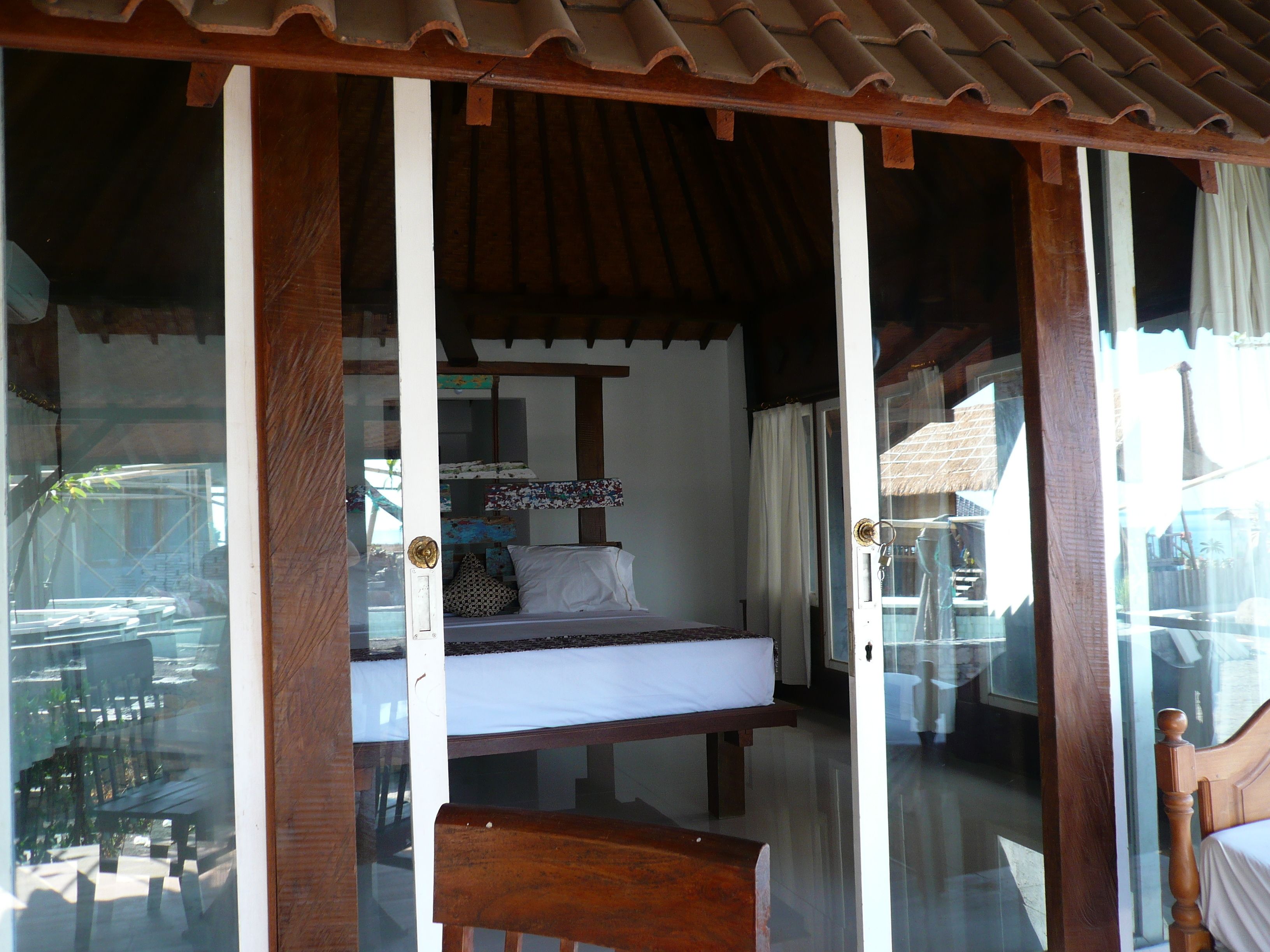 A room with a bed, a bench, and a glass door leading outside.