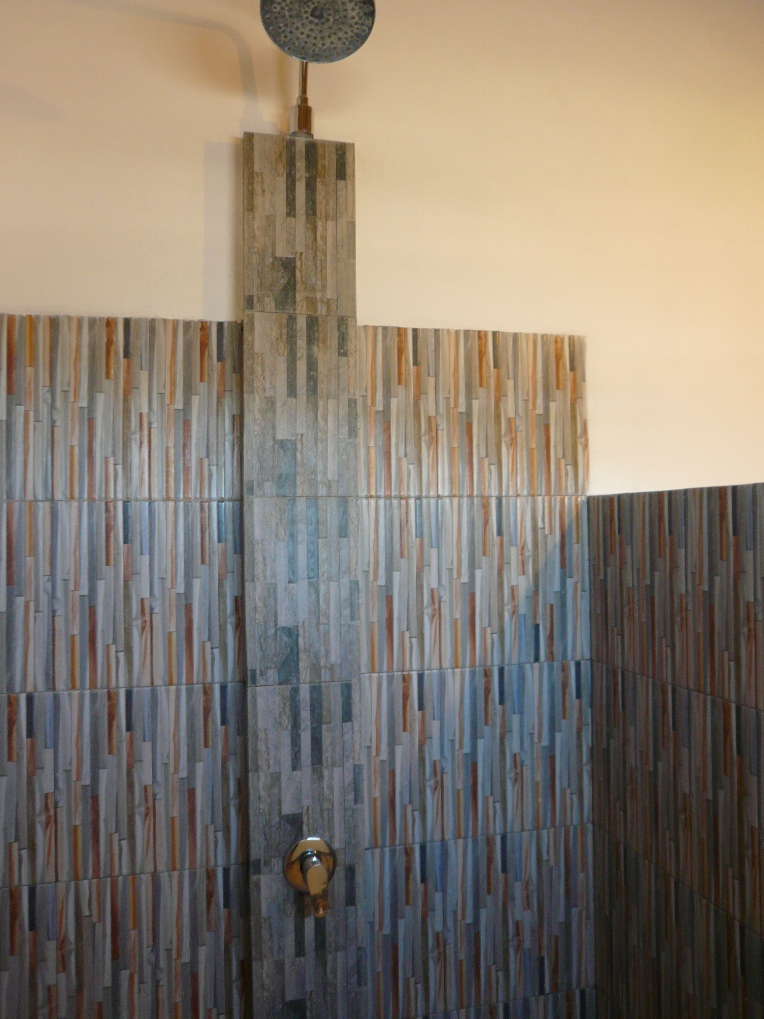 A shower with a vertical panel design and a round light fixture above it.