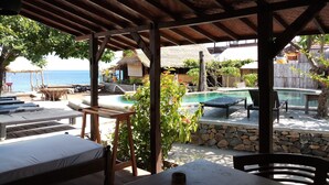 Un espacio al aire libre cubierto con piscina, sillones reclinables y una cama.