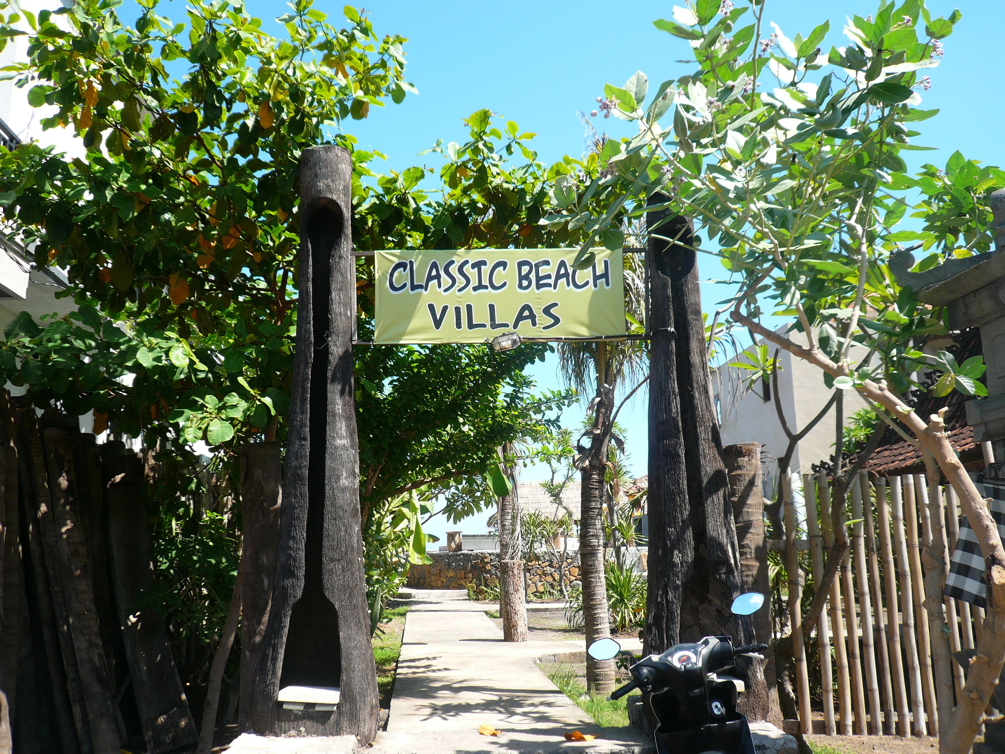Un letrero que dice 'Classic Beach Villas' sobre un camino que lleva a un edificio.