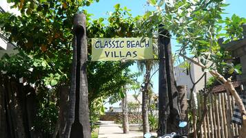 Un letrero que dice 'Classic Beach Villas' sobre un camino que lleva a un edificio.