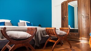 A room with a bed, two wooden chairs, a wardrobe, and a blue wall. - Félix dOrt (Lyon)