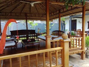 A wooden deck with a thatched roof, wooden furniture, and potted plants. - Starlight Restaurant & Bungalows (Buleleng)