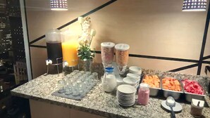 Distribución tipo bufé con diversos alimentos y dispensadores de bebidas.