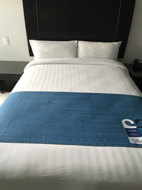 A hotel room with a bed, a headboard, and a nightstand with a lamp. - Hotel Rosgaud (Córdoba)