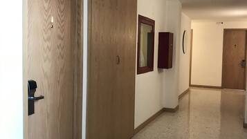 Un couloir avec des portes en bois, un miroir et un tableau encadré accroché au mur.