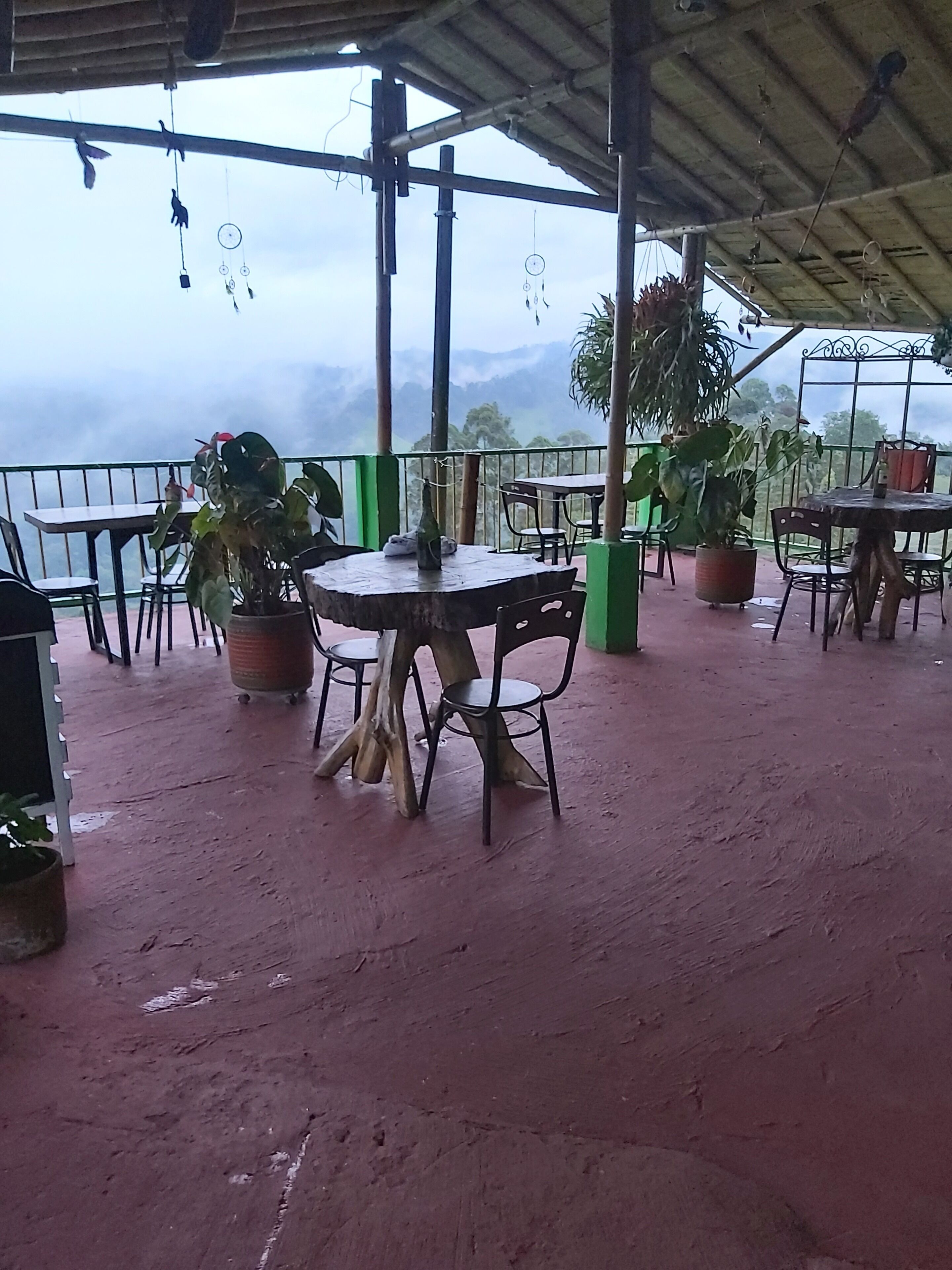 An outdoor patio with tables and chairs, potted plants, and a view of a mountainous landscape.
