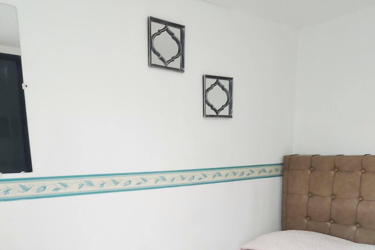 Ein Schlafzimmer mit einem Bett, einem Nachttisch aus Holz und zwei Wanddekorationen.