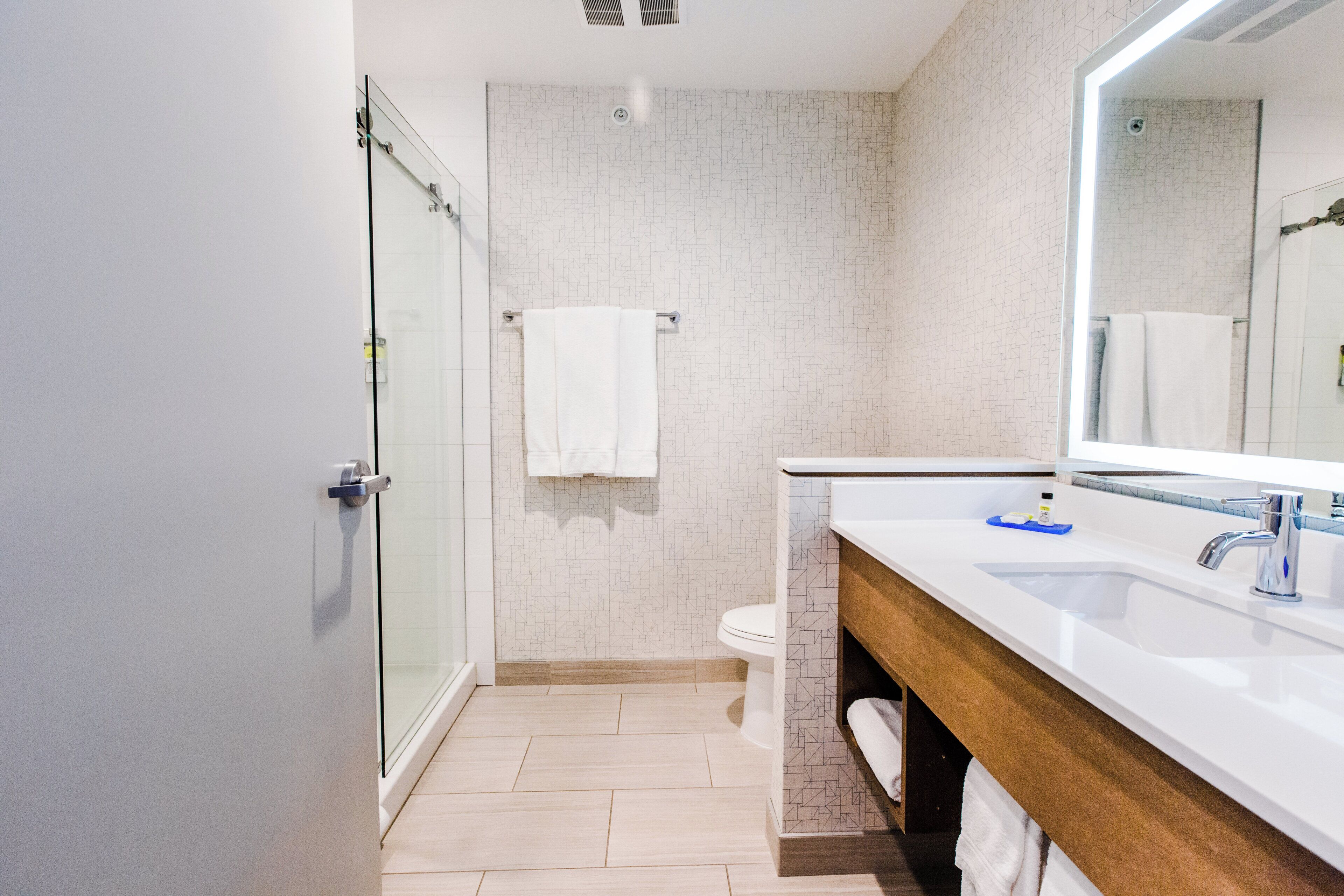 A modern bathroom with a glass shower enclosure, a white toilet, and a vanity with a mirror.