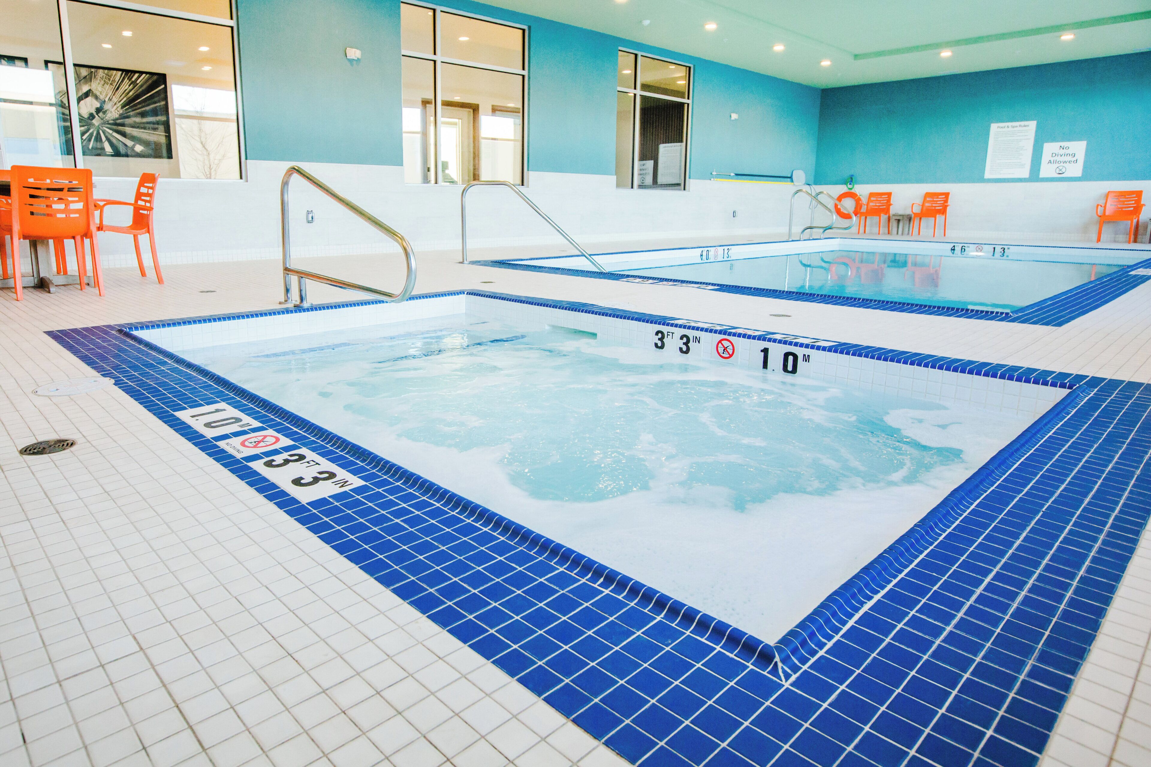 An indoor swimming pool with clear water, marked depth lines, and a tiled floor.