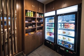 A vending area with shelves stocked with snacks and a refrigerator with beverages. - Holiday Inn Express & Suites West Edmonton - Mall Area by IHG (Edmonton)