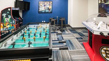 Relax and play in this room featuring a foosball table, arcade machines, and a TV.