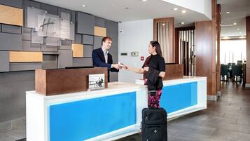 A hotel reception desk with a modern design, a digital display, and a fire alarm.