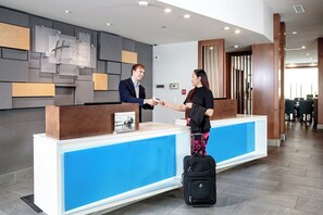 Una recepción de hotel con diseño moderno, una pantalla digital y un detector de incendios.
