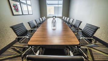 Una sala de conferencias con una larga mesa, sillas negras y piso alfombrado.