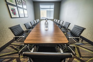 A conference room with a long table, black chairs, and a carpeted floor.