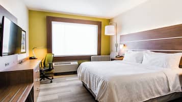 A hotel room with a bed, desk, chair, television, and a window with a view.