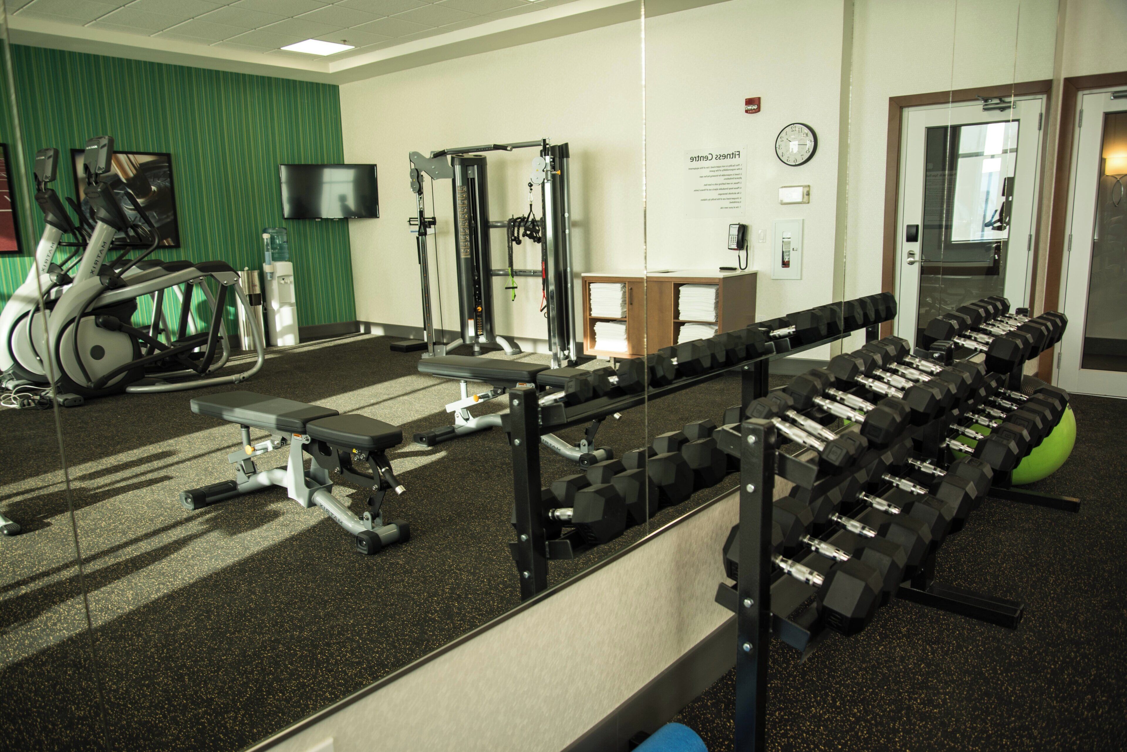 A gym with exercise equipment, a water dispenser, and a clock on the wall.