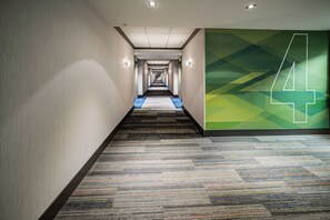 A hotel hallway with carpeted flooring, a green wall with a white number '4', and recessed lighting. - Holiday Inn Express & Suites West Edmonton - Mall Area by IHG (Edmonton)