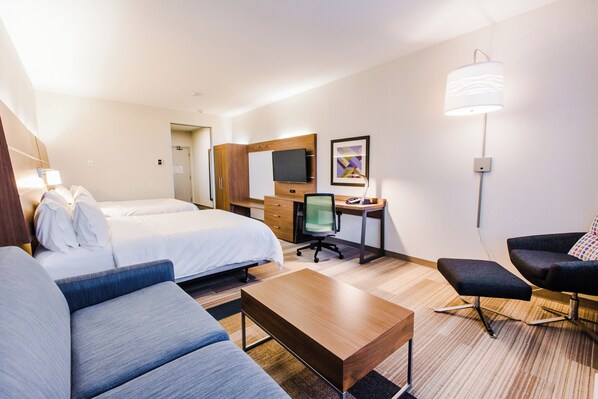 A hotel room with a bed, a desk, a chair, a sofa, and a lamp.