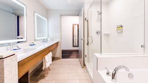 Un baño moderno con dos lavamanos, un espejo grande, zona de ducha y tocador de madera.
