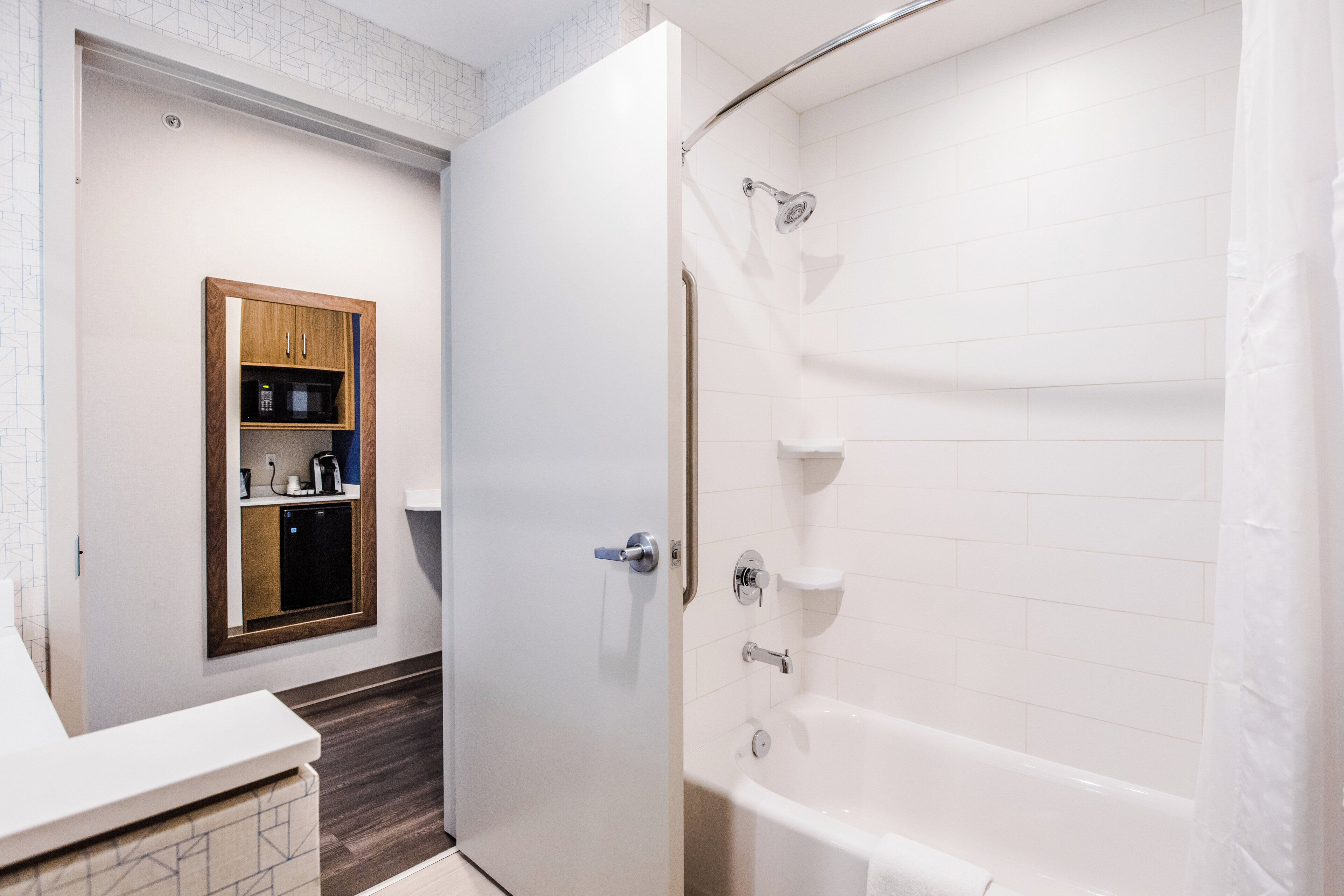 Une salle de bain avec une baignoire blanche, un meuble en bois contenant un four à micro-ondes et un espace douche.