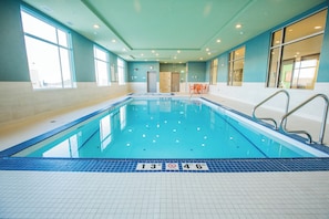 Une piscine intérieure à l’eau claire, avec des lignes indiquant la profondeur et un panneau indiquant qu’il est interdit de plonger.
