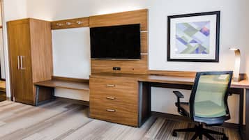 A modern office space with a desk, chair, television, and storage cabinets.